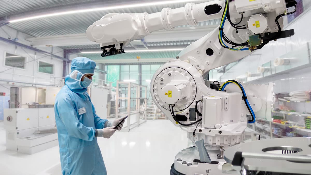 An engineer working alongside robotic automation in a cleanroom